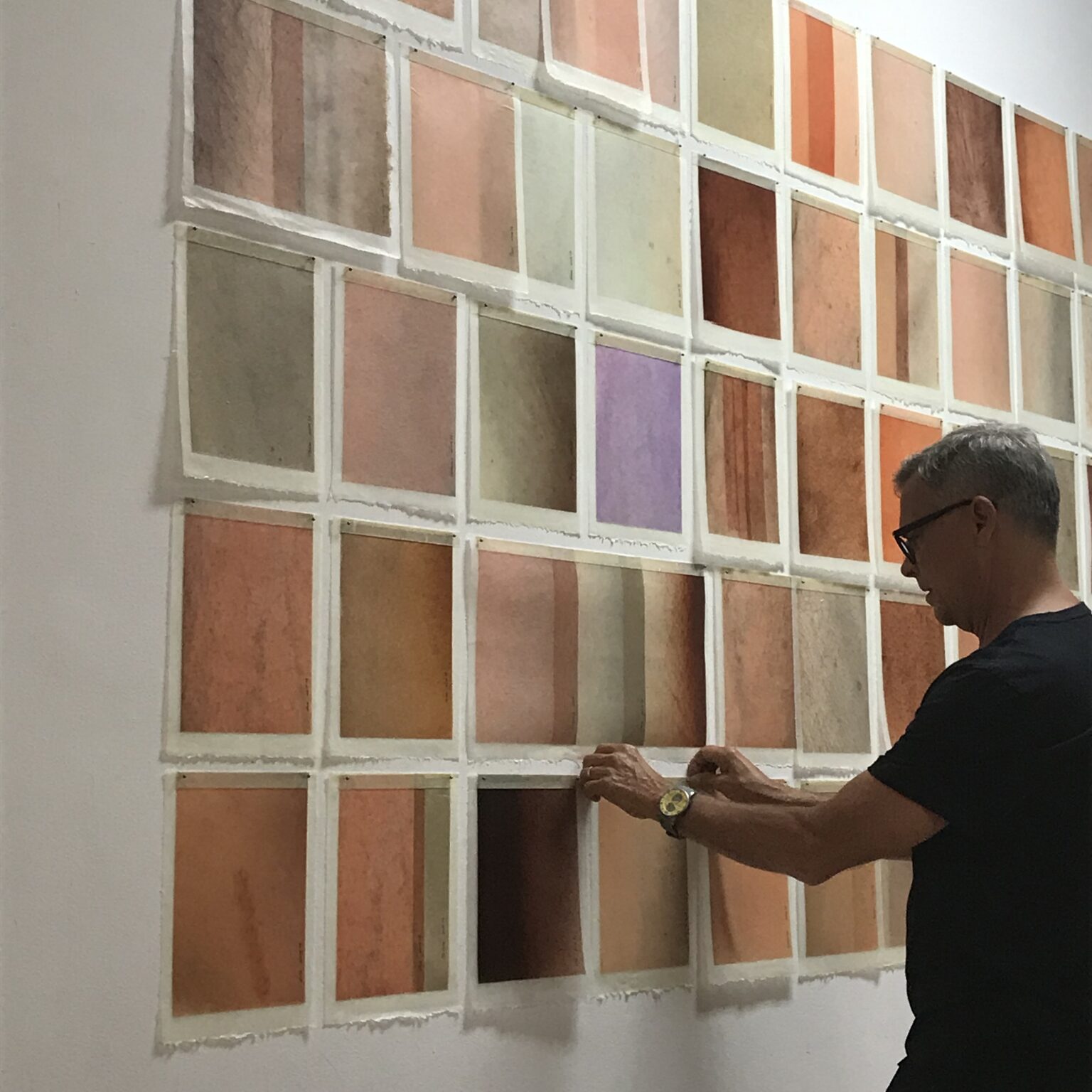 A man is looking at the wall of wood samples.
